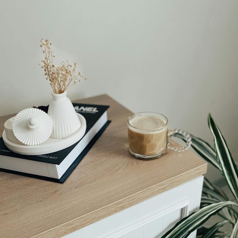 business information A coffee cup beside a decorative vase and a book on a wooden surface.