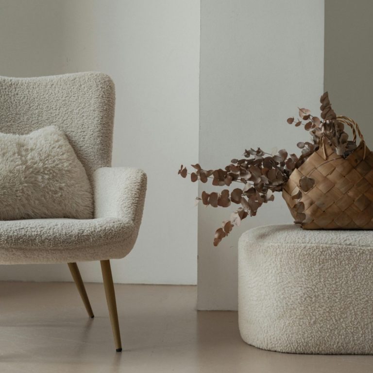 Home Decluttering and organising A soft-textured armchair and ottoman with a decorative dried flower arrangement.