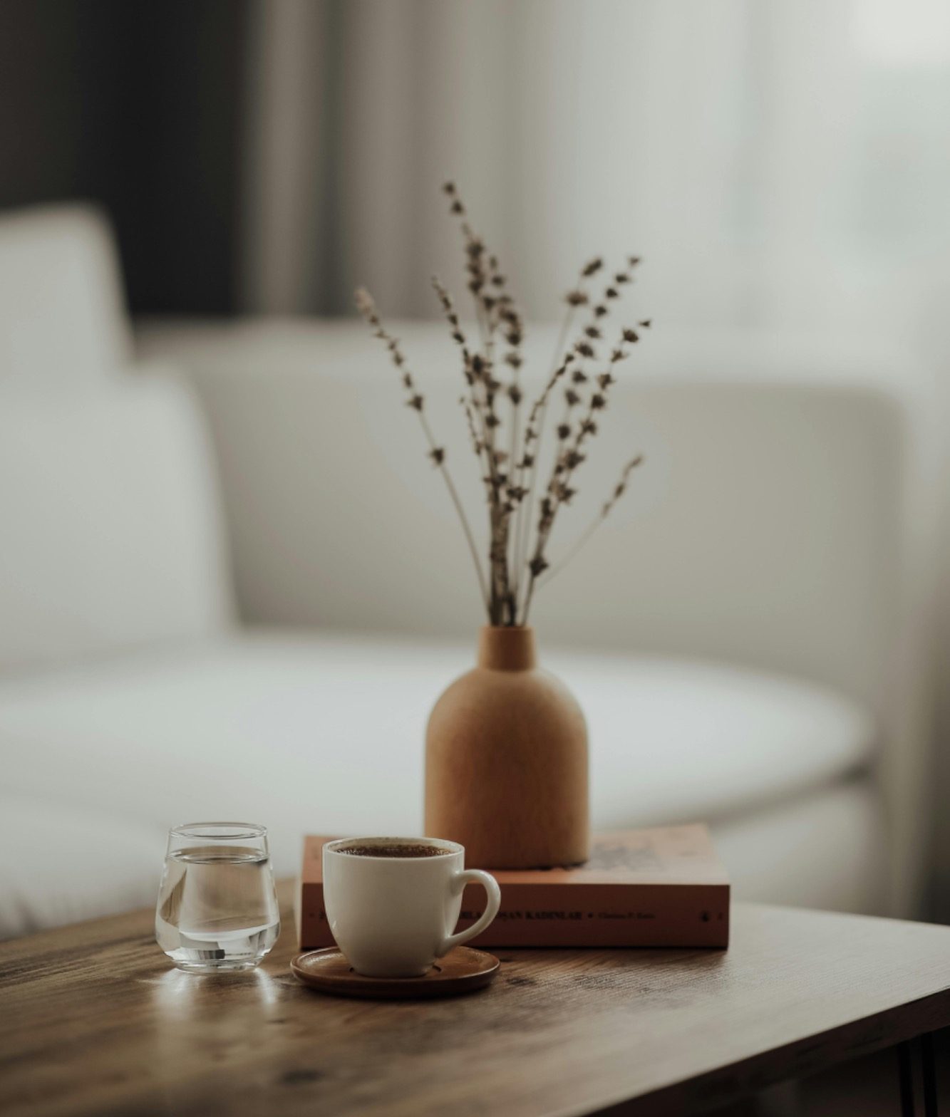 Home organising services in Milton Keynes A small vase with dried branches next to a coffee cup on a wooden table.