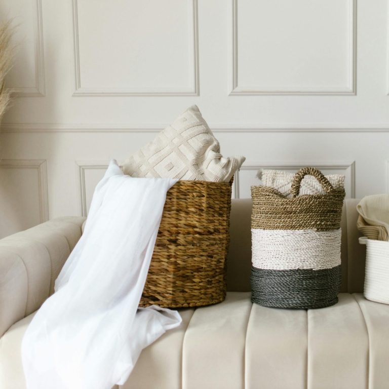 Domestic cleaning in Milton Keynes Two woven baskets with cushions on a light sofa against a textured wall.
