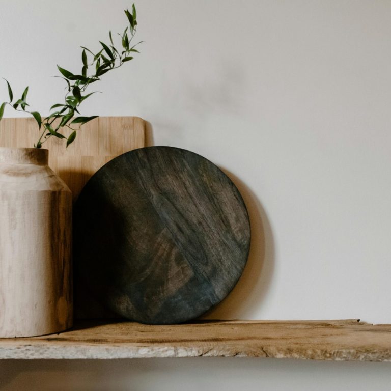 Kitchen makeover package A dark wooden plate, a vase, and cutting boards on a rustic shelf with greenery.